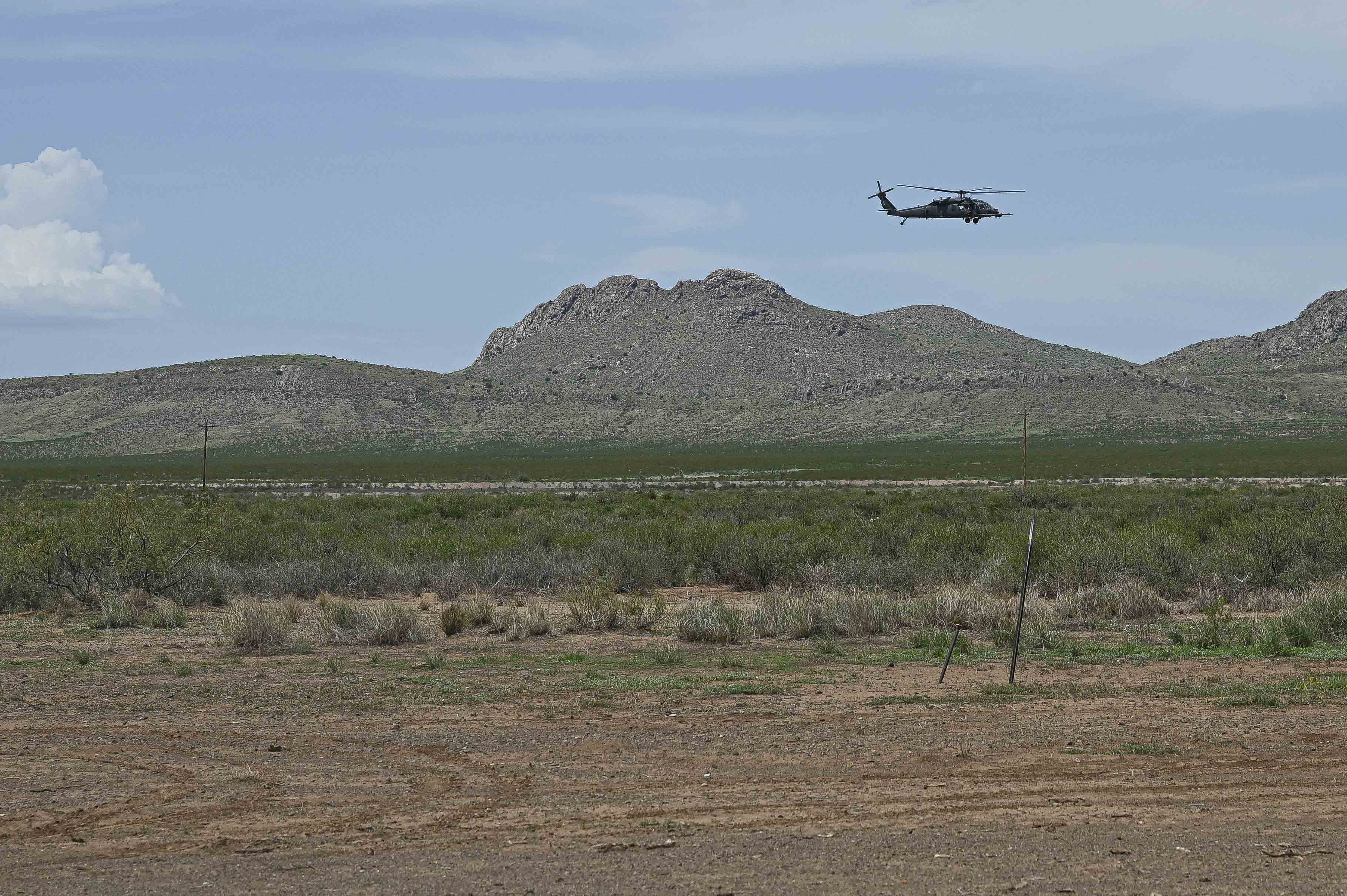 Image shows a helicopter flying over the desert.